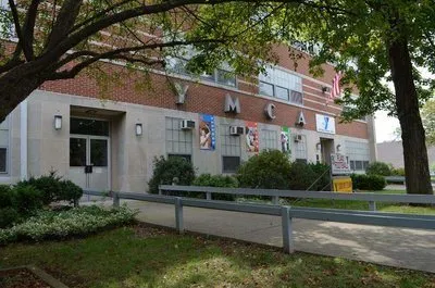 The brick exterior of the Pocono Family YMCA seen from the road behind mature trees.