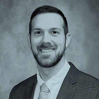 Christian Lichty in a suit and tie against a grey studio backdrop.